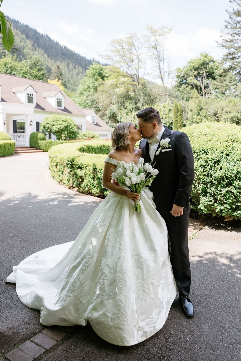 A bride and groom share an emotional moment outdoors surrounded by lush greenery.
