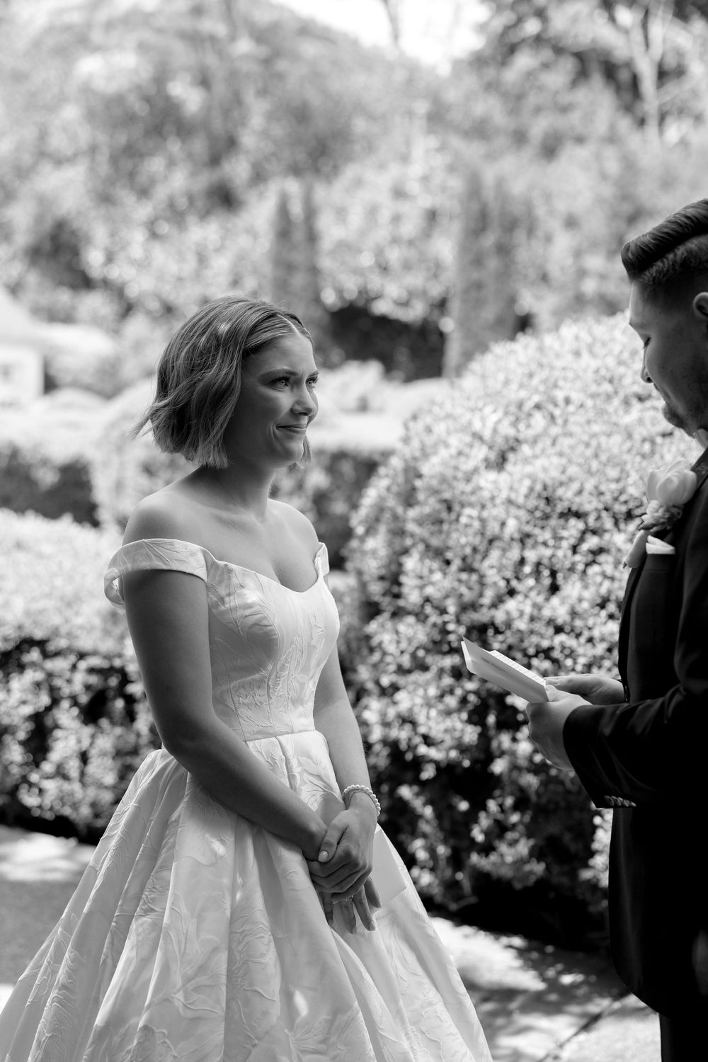 Black and white wedding photo sequence showing a bride in an elegant off-shoulder gown during an outdoor garden ceremony.