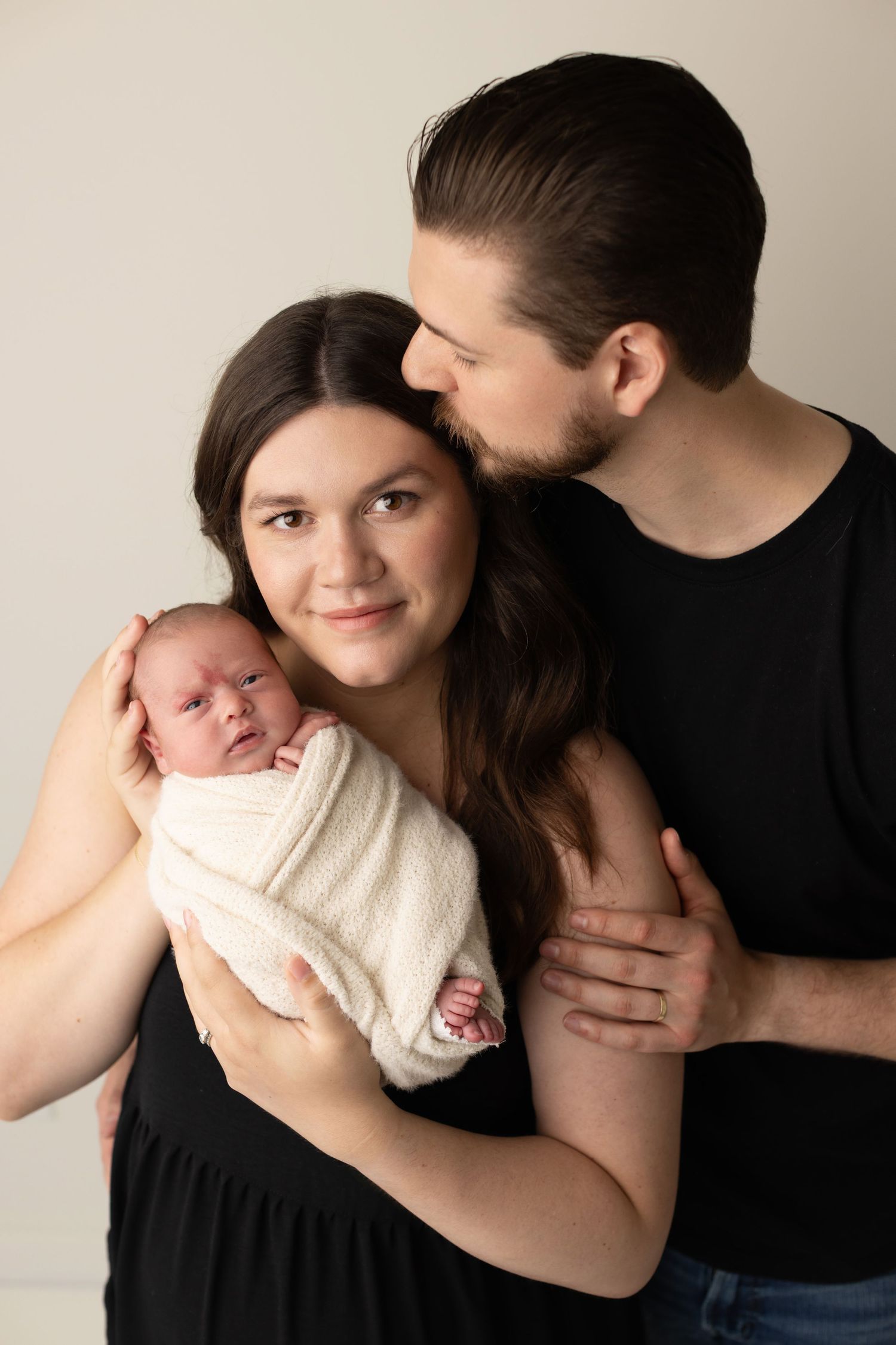 A series of intimate black and white family portraits showing tender moments with a newborn baby.