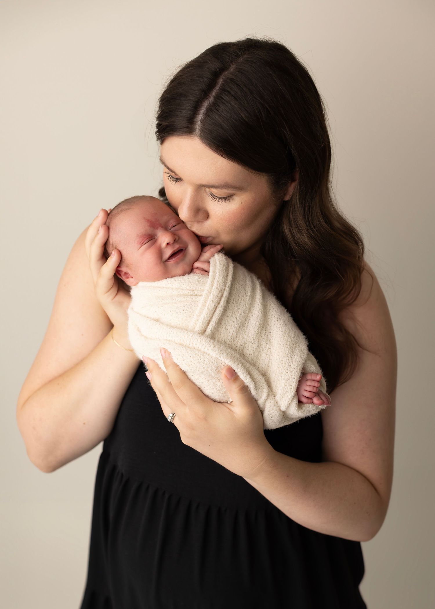 Four sequential photos show a tender moment between parent and newborn baby in black and white tones.