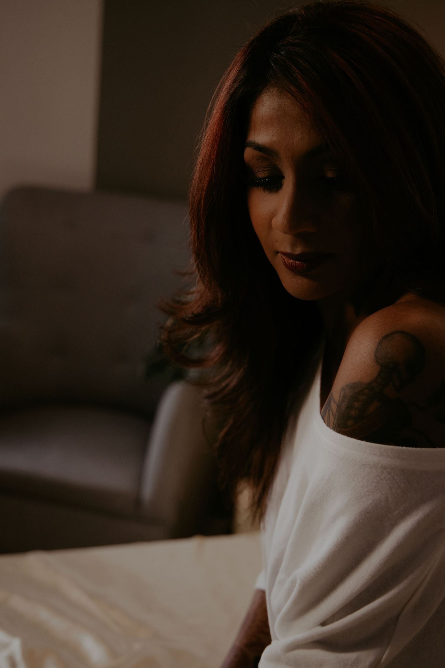 A person with curly hair lying on white bedding in a dreamy boudoir photoshoot sequence.