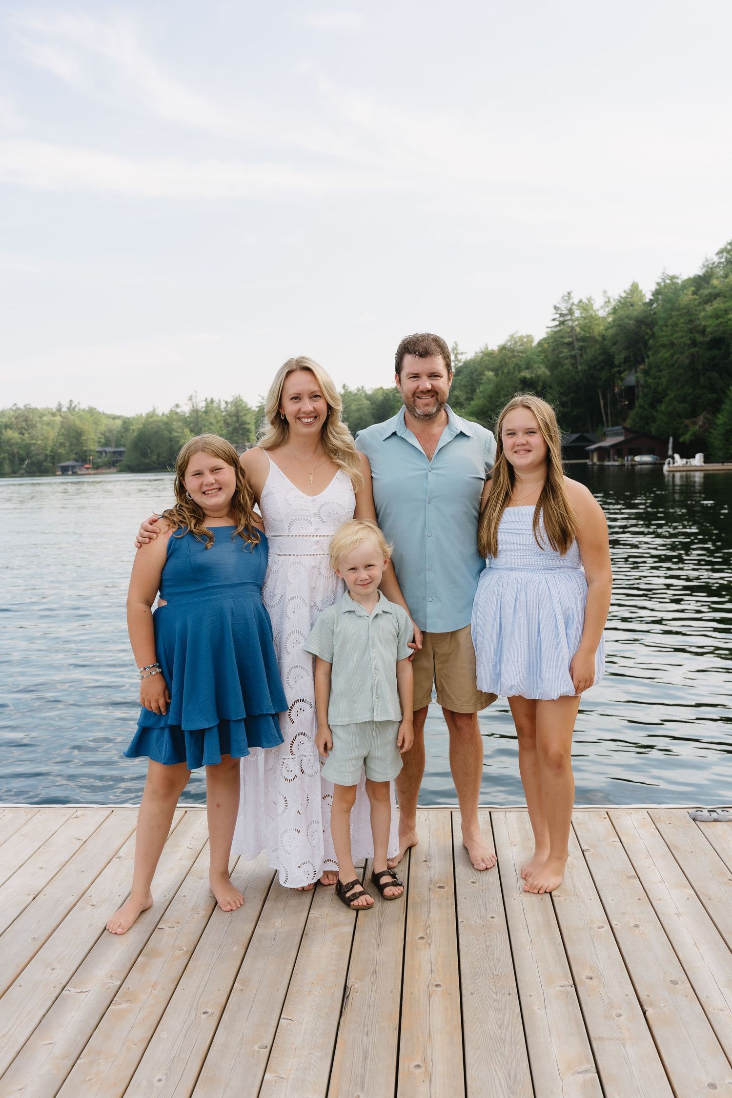 A family portrait on a wooden dock by a serene lake.