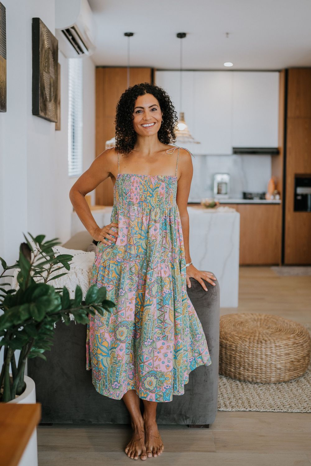 Floral print sundress shown in modern interior with woven basket decor and plants.