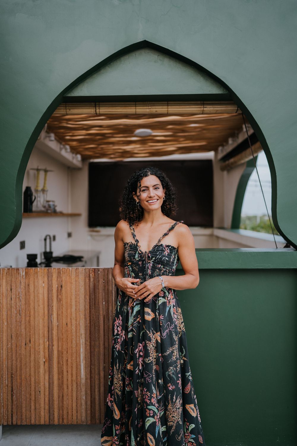 Floral print maxi dress showcased against green wall with arched window detail.