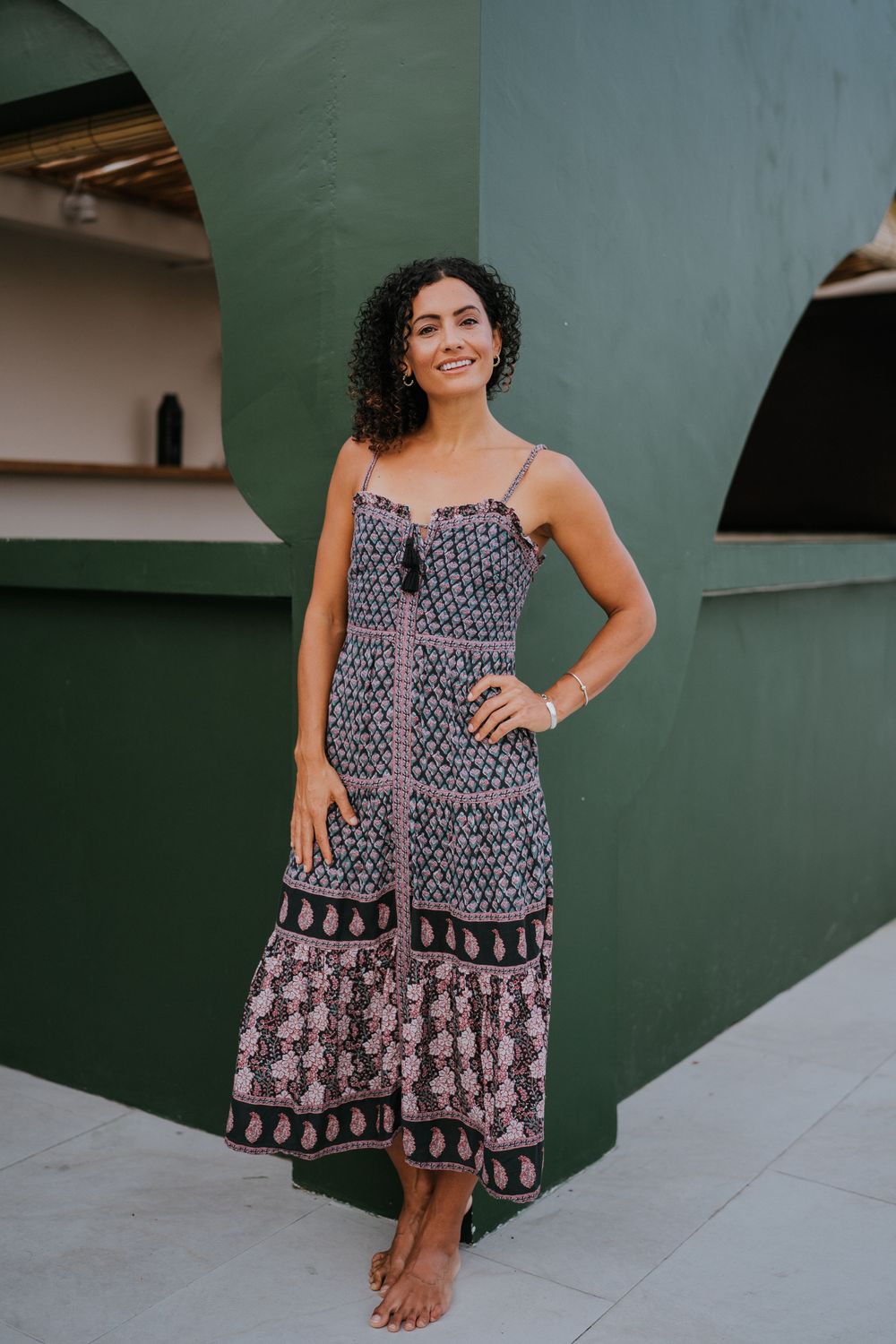 Navy and white patterned sundress displayed against green wall outdoors.