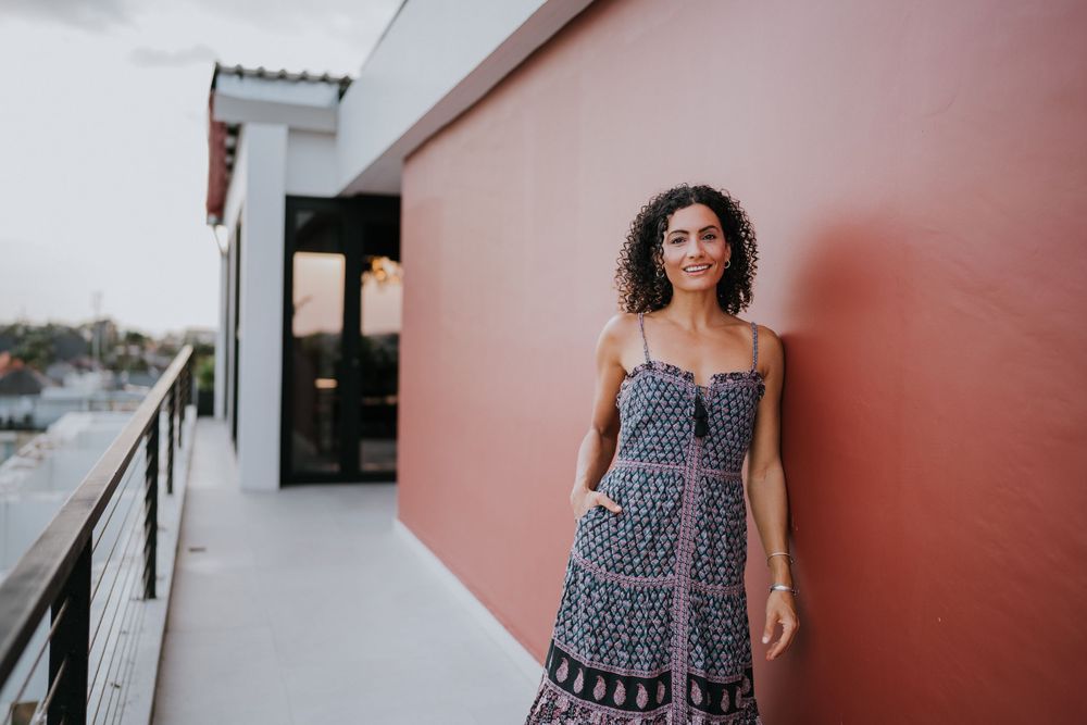 Navy printed summer dress styled against pink and white exterior wall.