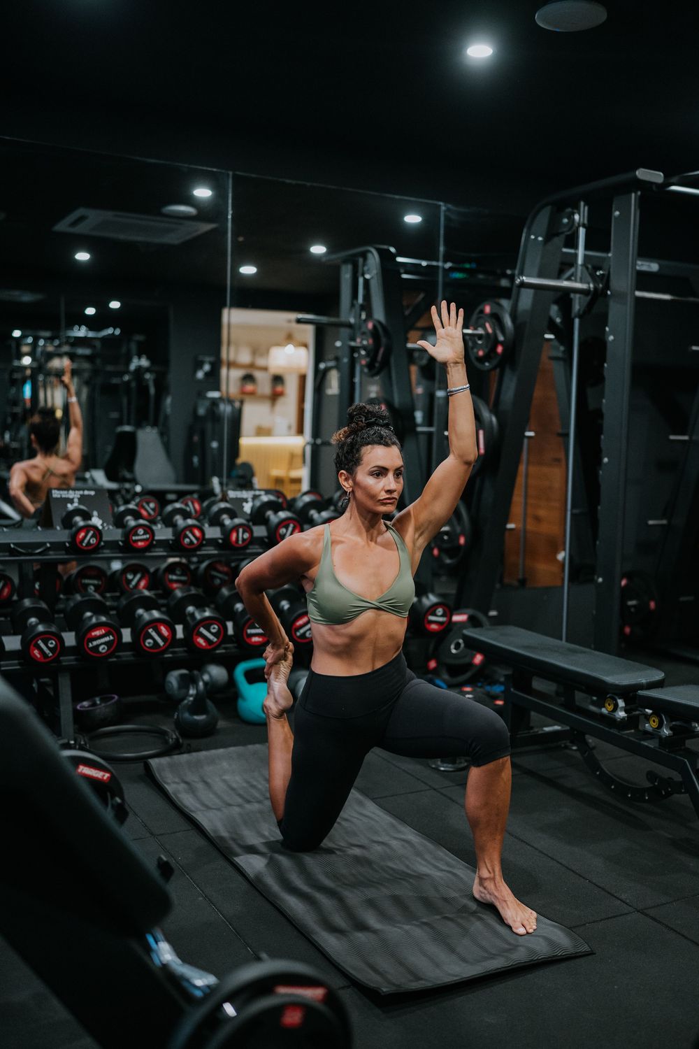 Advanced bodyweight exercises performed on gym mat with mirror backdrop.