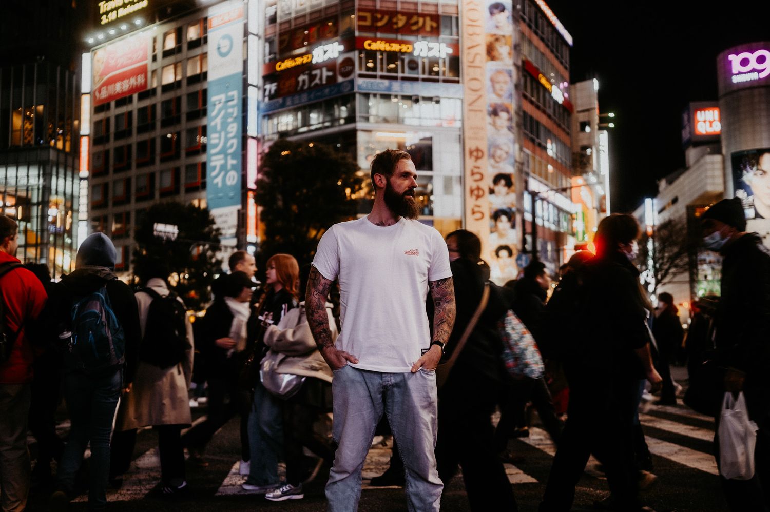 Crowds of people walking at night in a busy urban street with bright neon signs and storefronts.
