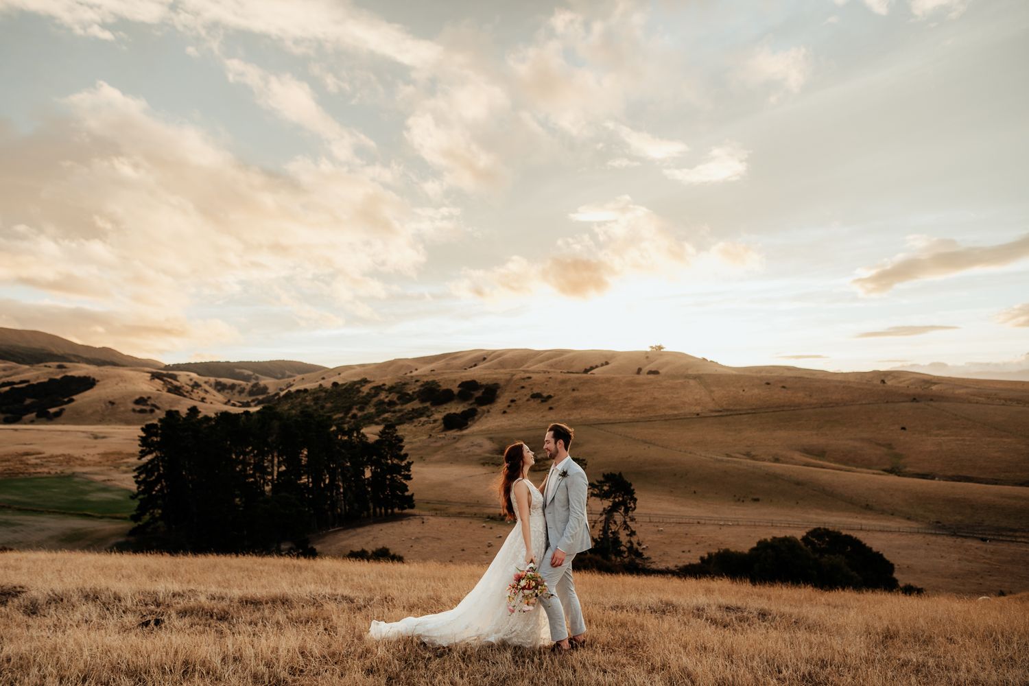 A romantic wedding photo session at sunset in rolling golden hills of Wairarapa with dramatic cloudy candy floss skies by August & Vine