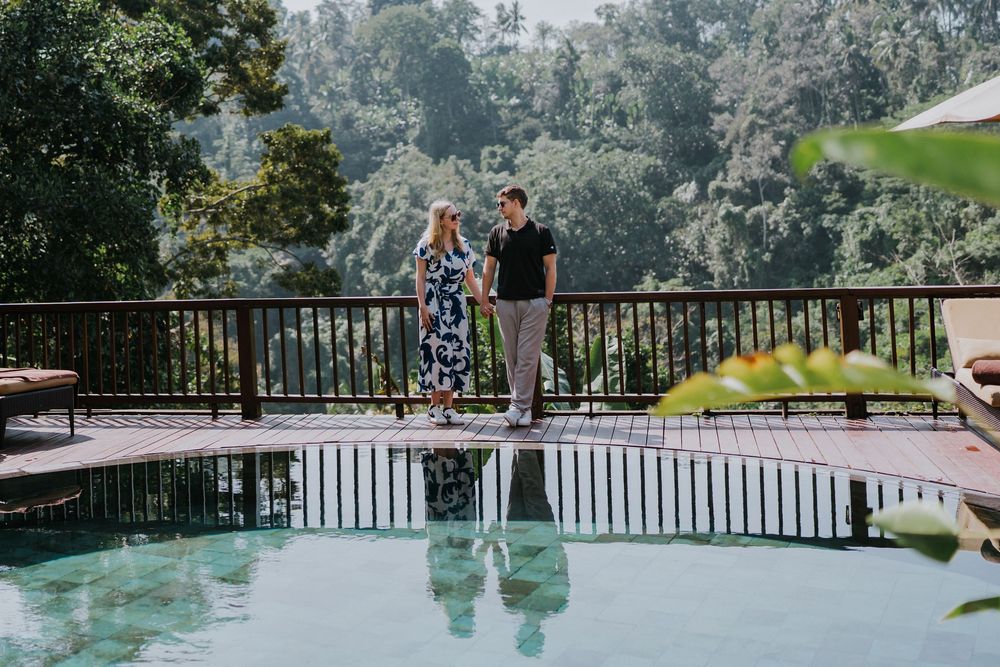 A couple stands on a wooden viewing platform overlooking a scenic forest landscape.