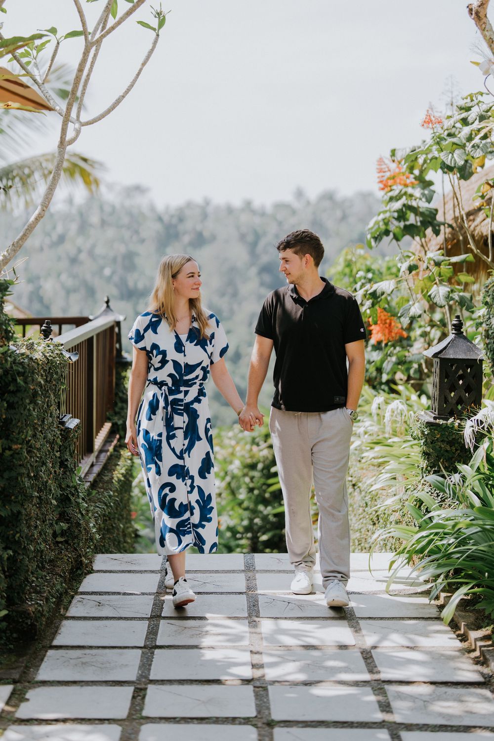 Couple strolling along a tropical garden pathway with mountain views.
