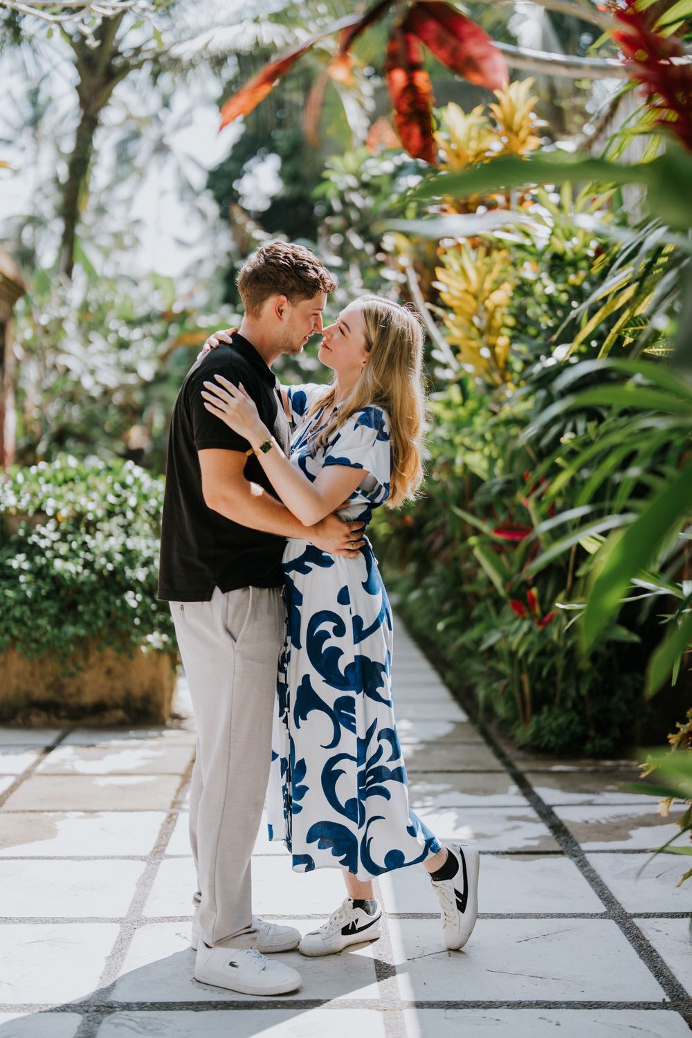Romantic moment between couple in tropical garden setting with stone pathway.