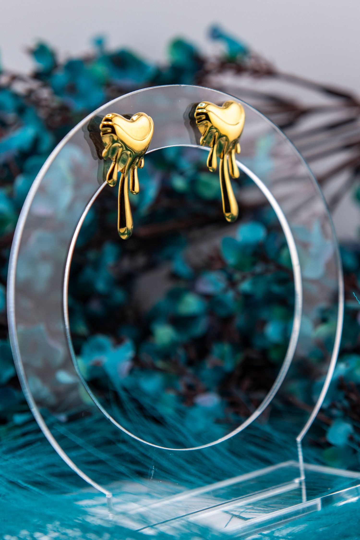 Decorative gold bird ornaments displayed on clear circular stands against teal background.
