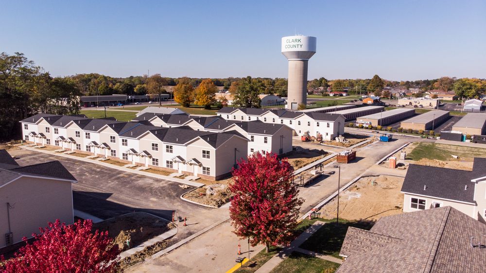 Aerial panoramic view of a suburban neighborhood with autumn trees, homes, and streets on a sunny day.