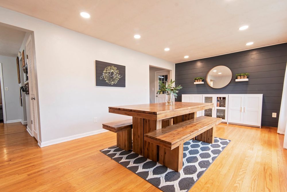 Spacious room with hardwood floors and geometric area rug under dining table.