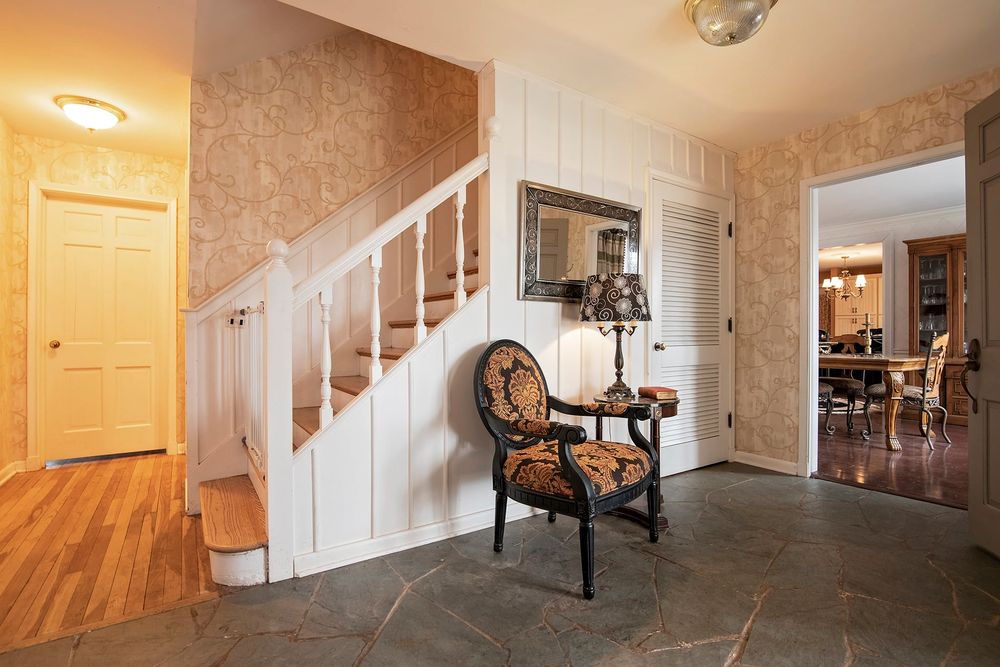 Long hallway with hardwood flooring and white walls featuring traditional decor.