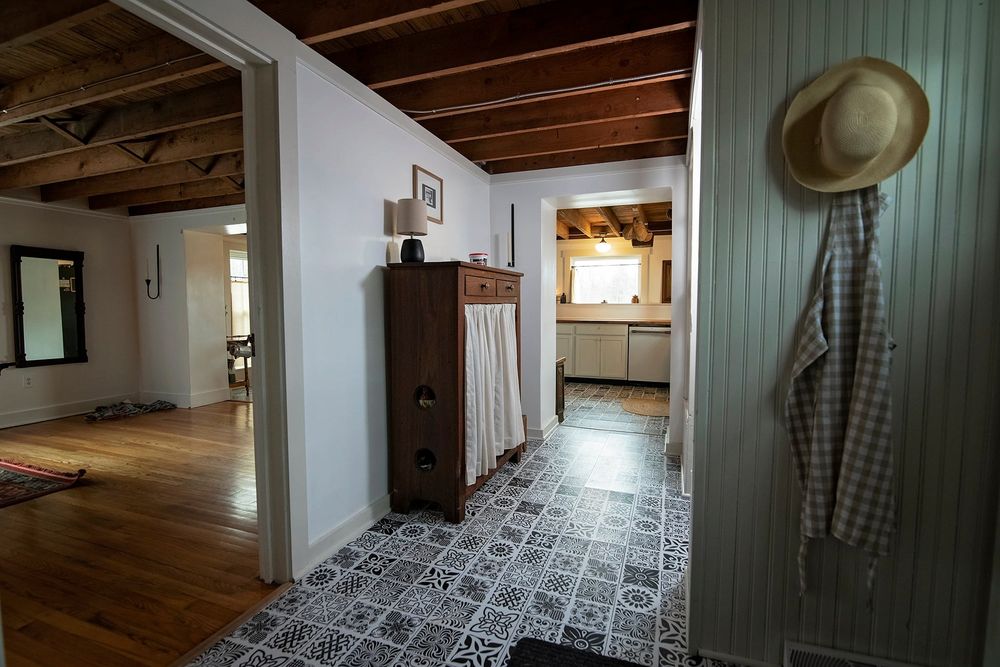 Basement hallway with grey tile flooring and wood beam ceiling details.