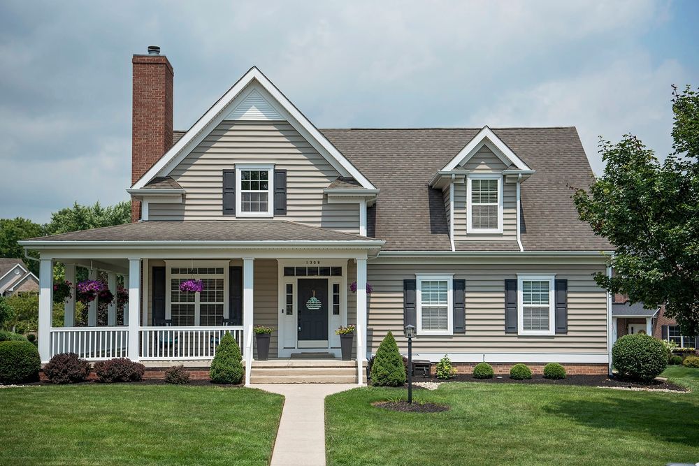 Cape Cod style home exterior with grey siding, white trim, and dormer windows.