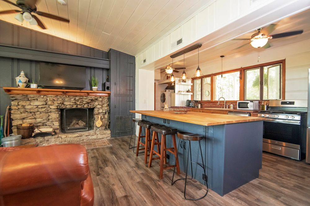 Open concept kitchen and dining area with dark wood cabinetry and stone accent wall.