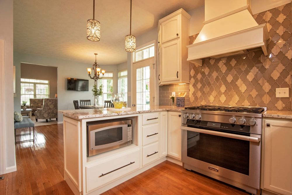 Modern kitchen with diagonal pattern backsplash and white cabinetry.