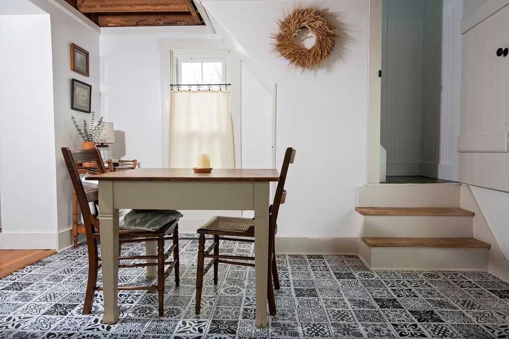 Contemporary dining area with patterned rug, wooden chairs, and sunburst mirror wall decoration.
