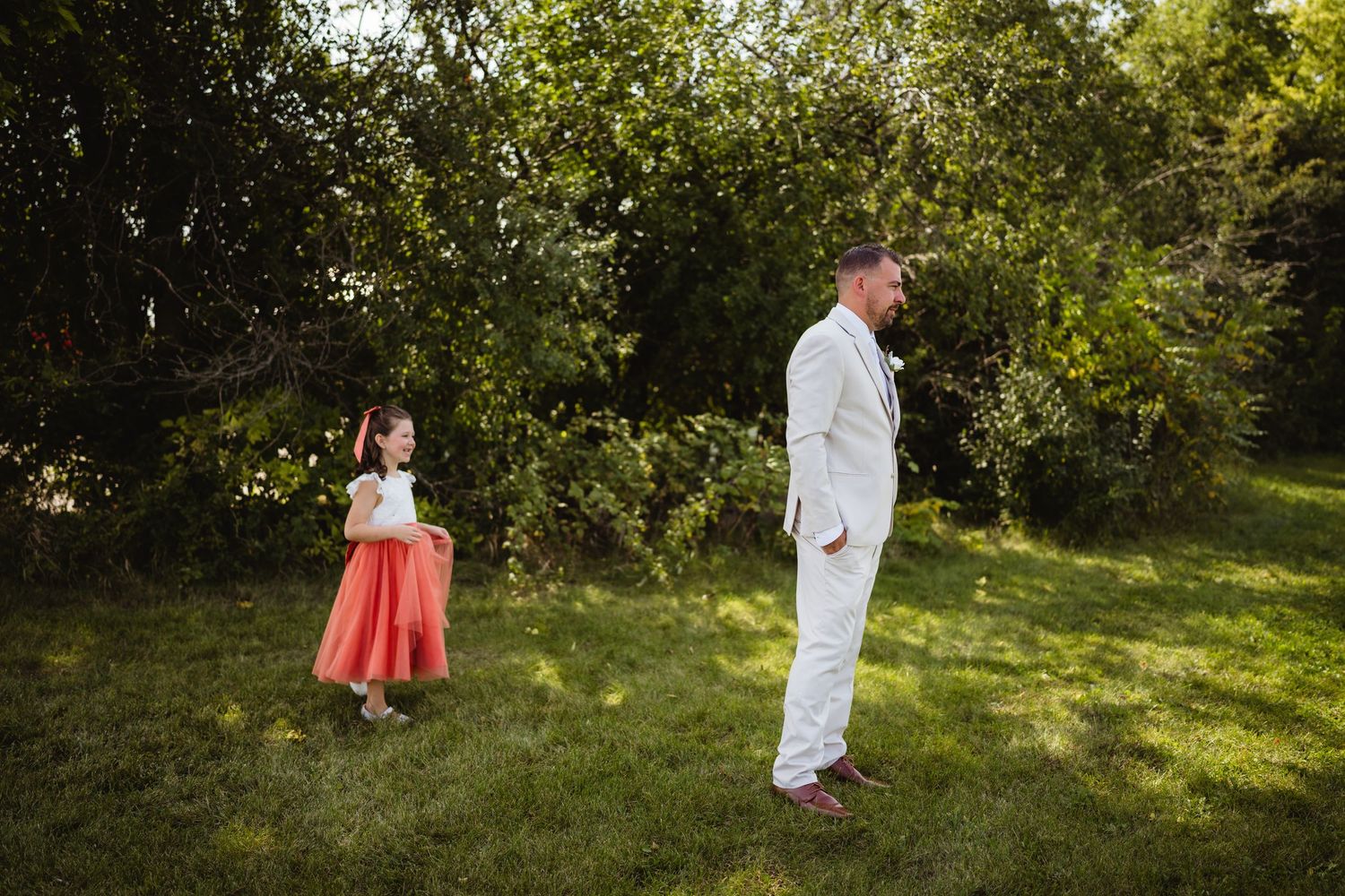 A couple walks through a sunlit orchard during a romantic summer photoshoot in a lush garden setting.
