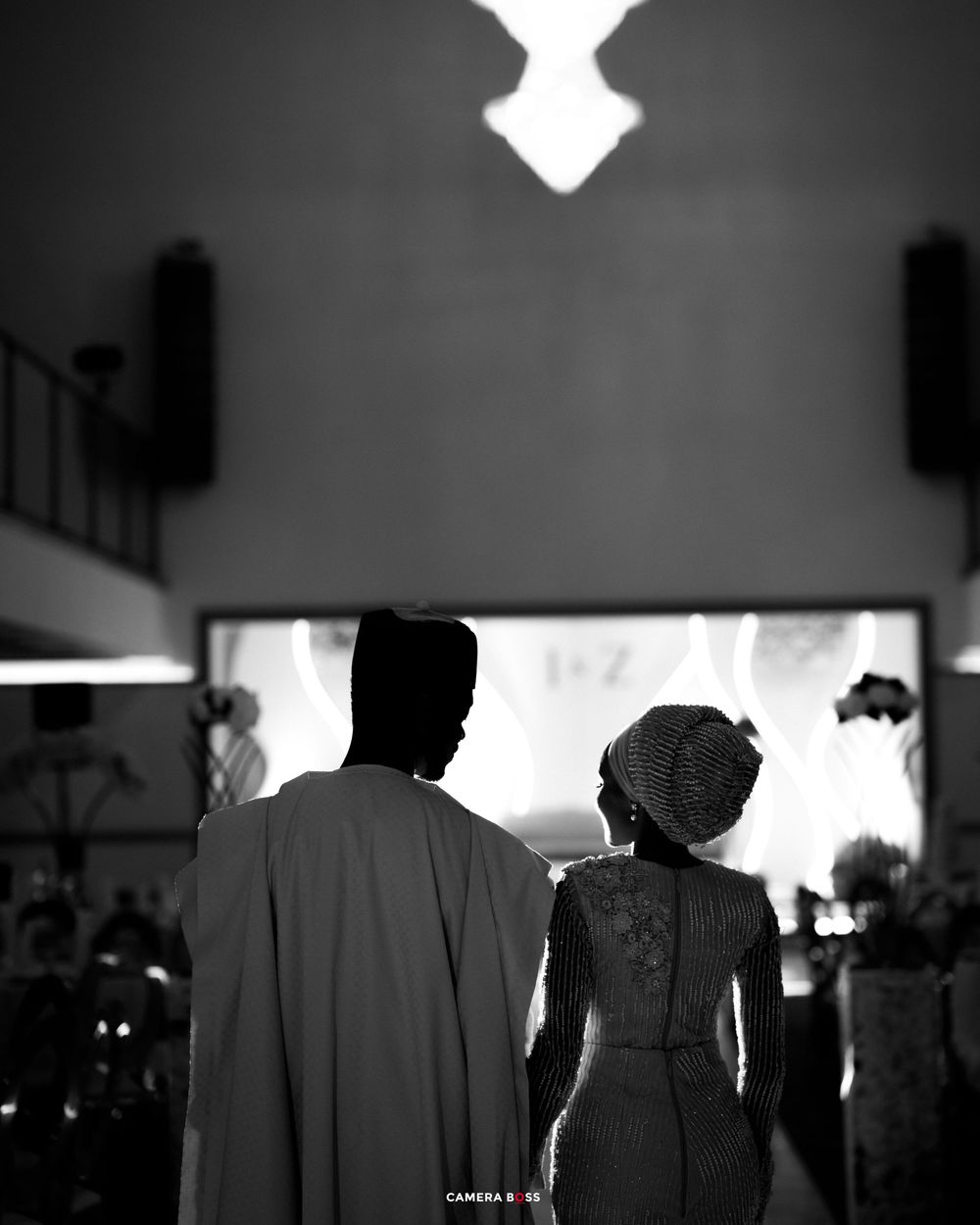 Dramatic black and white silhouettes of people lined up in an indoor setting creating a moody atmosphere.