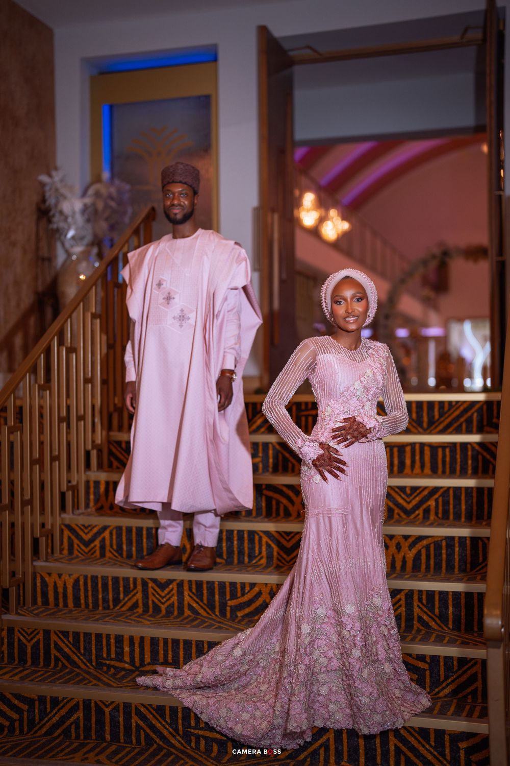 Wedding fashion photoshoot featuring elegant white traditional outfits with intricate embroidery details against wooden railing.