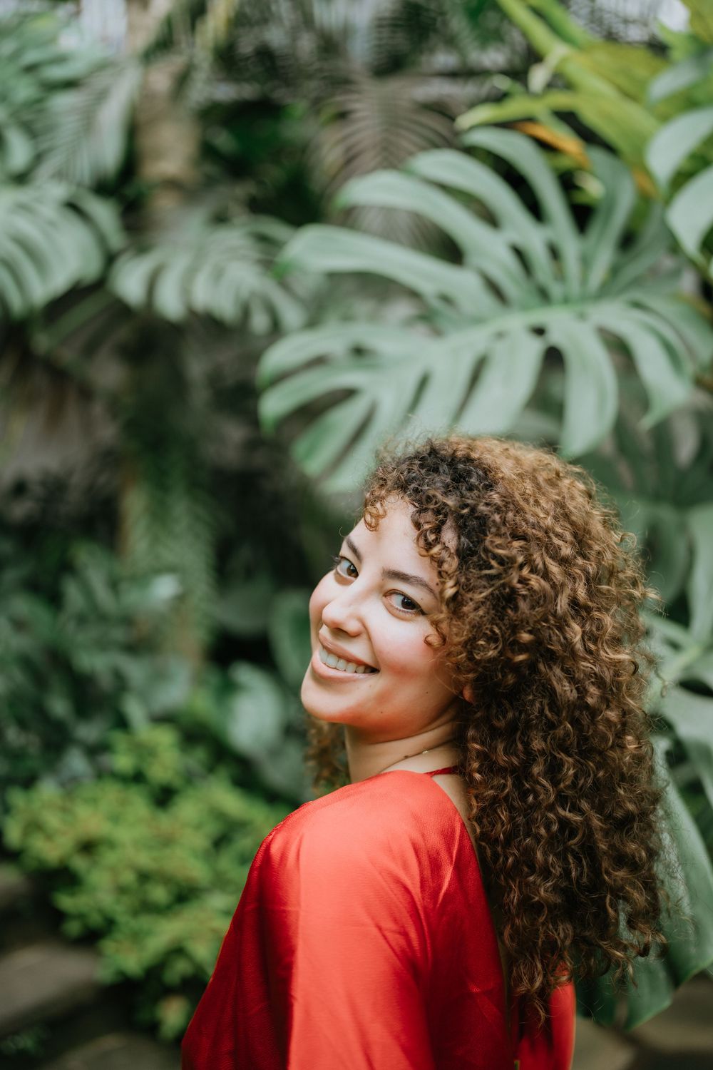 Vibrant red clothing contrasts beautifully against tropical monstera leaves in a garden setting.