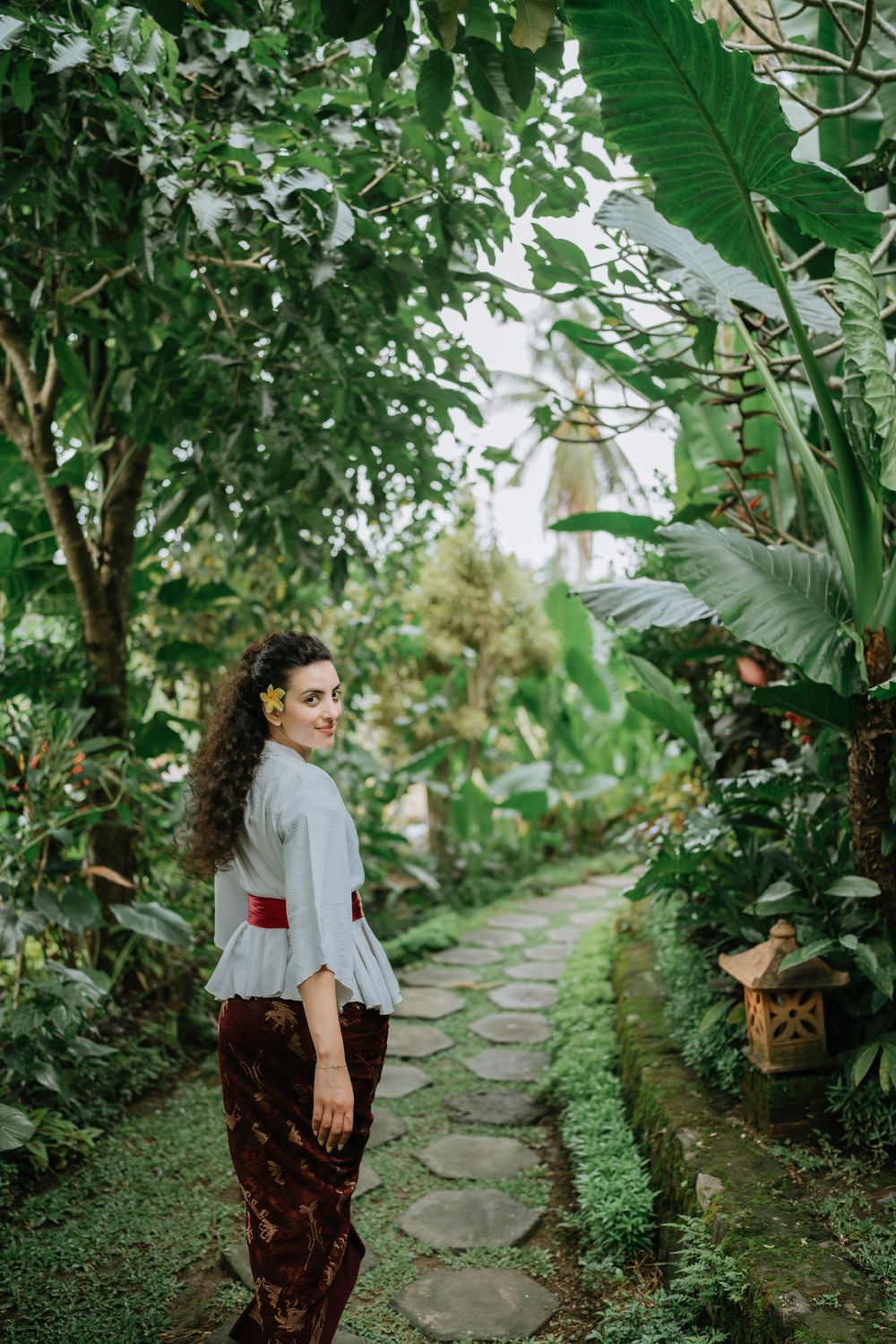 Person walking along stone pathway through lush tropical garden setting.