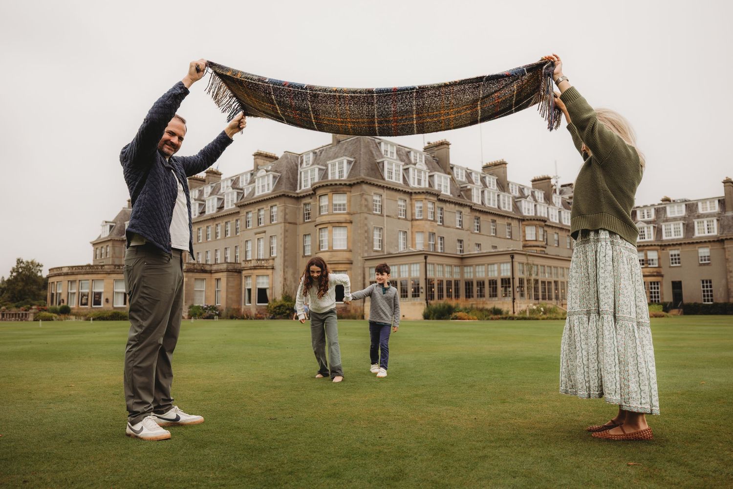A romantic outdoor proposal moment captured at a historic stone building with a golf course in the background.