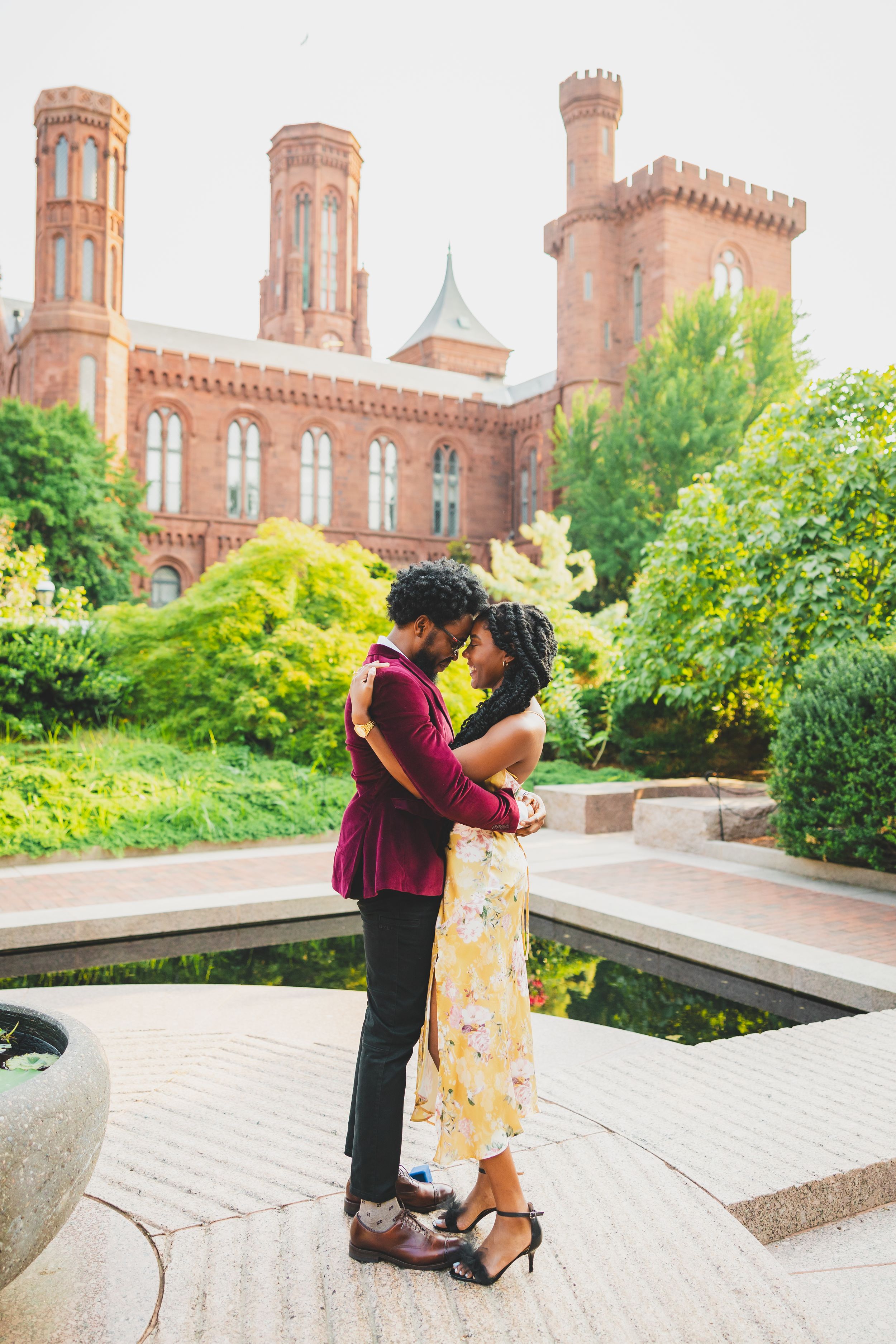 A romantic moment shared between a couple in front of the historic Smithsonian Castle with its distinctive red brick architecture.