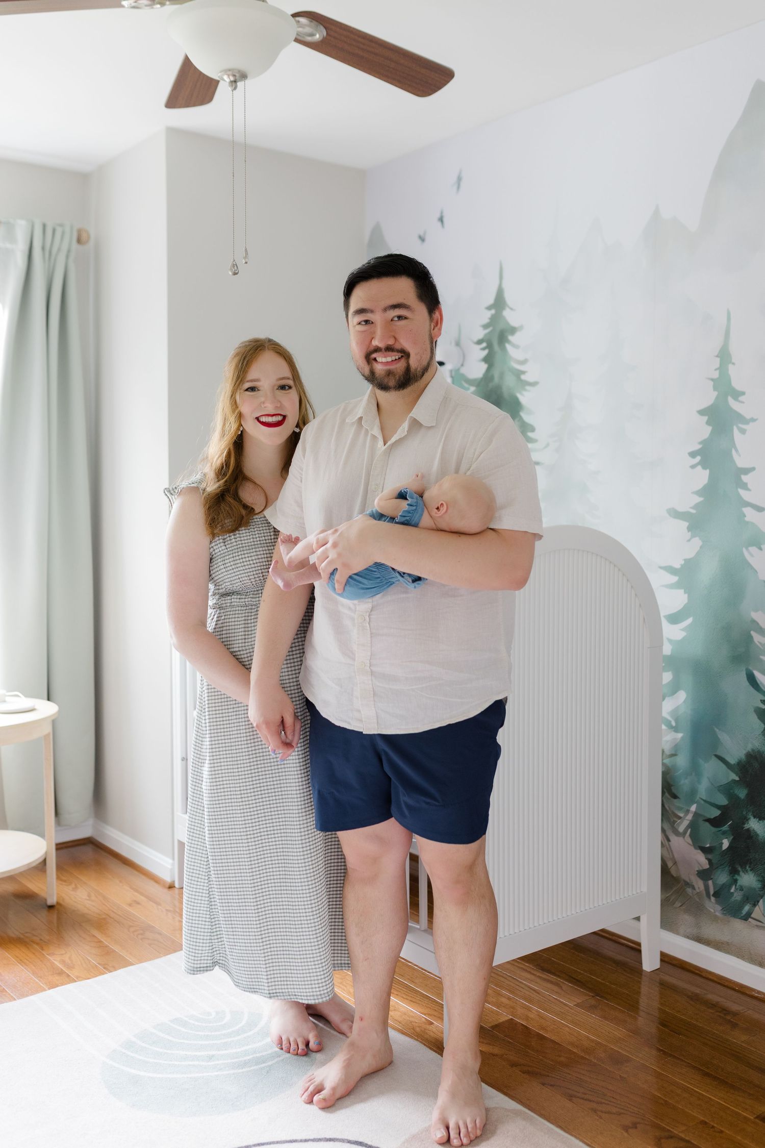 A nursery room with pine tree wall mural and hardwood flooring.