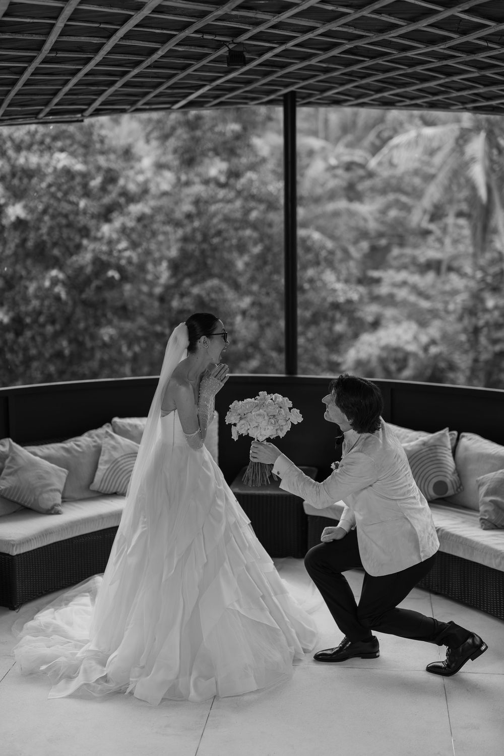 Black and white photo series captures playful moments between newlyweds on a covered patio.