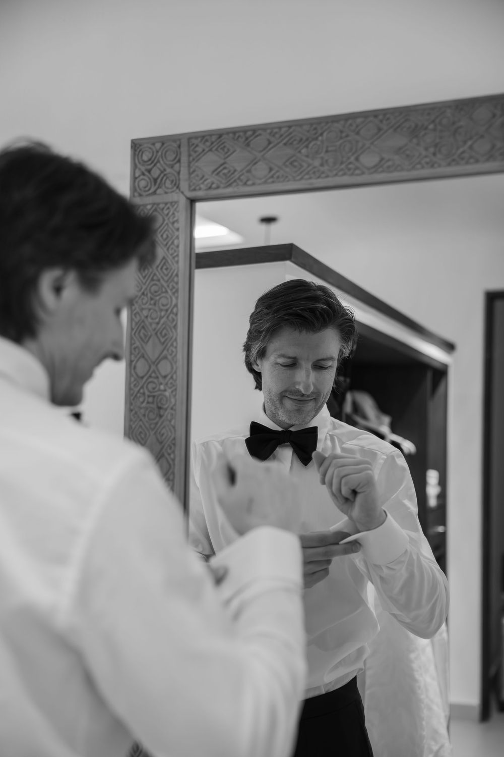 Black and white sequence showing preparation moments with formal attire and bow tie adjustments.
