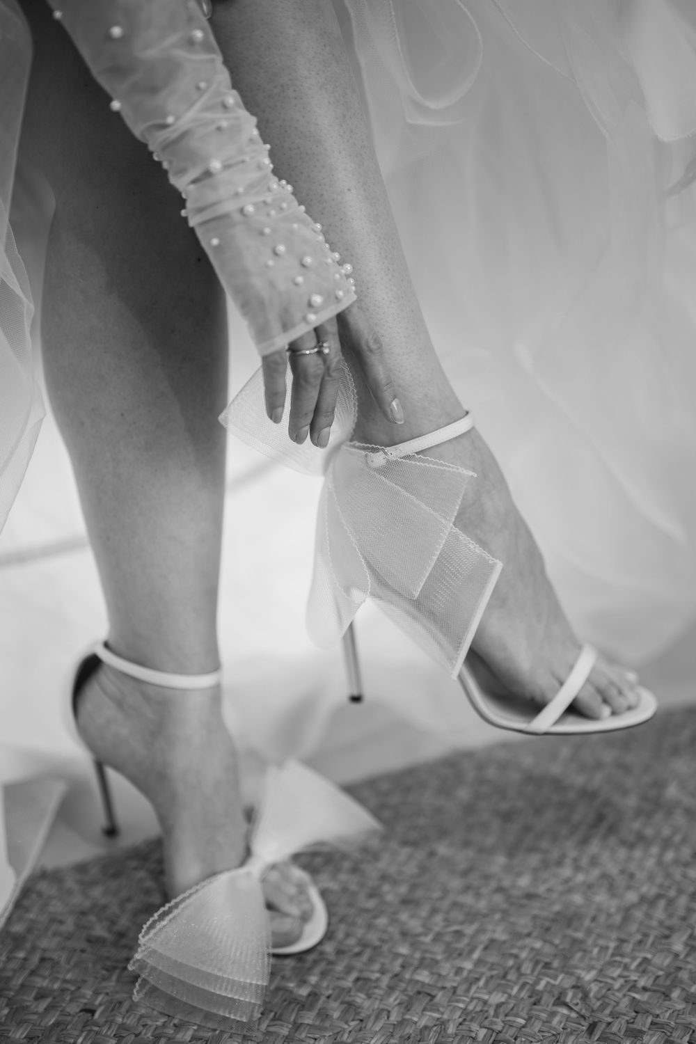 Close-up shots of white bridal shoes being put on against a carpeted floor.