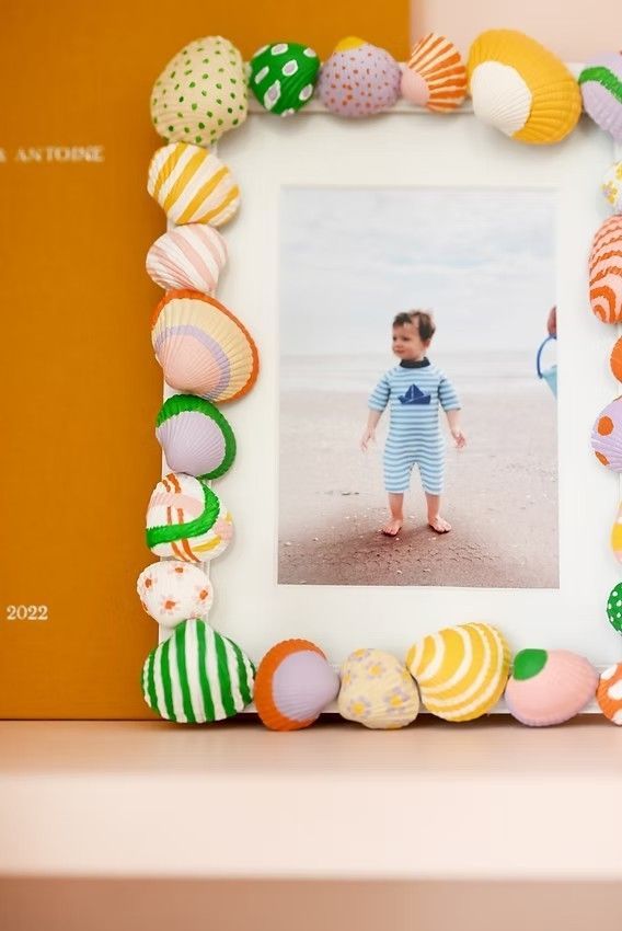 A set of decorative seashell-themed photo frames in orange, green and white colors displayed on a white surface.