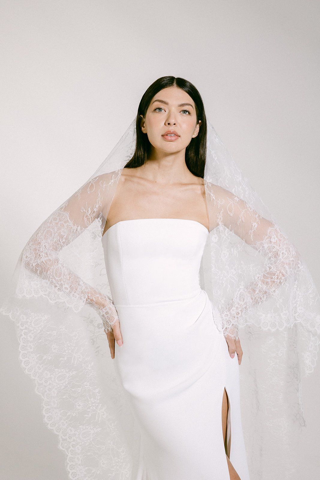 Modern bridal gown with strapless neckline and dramatic lace veil.