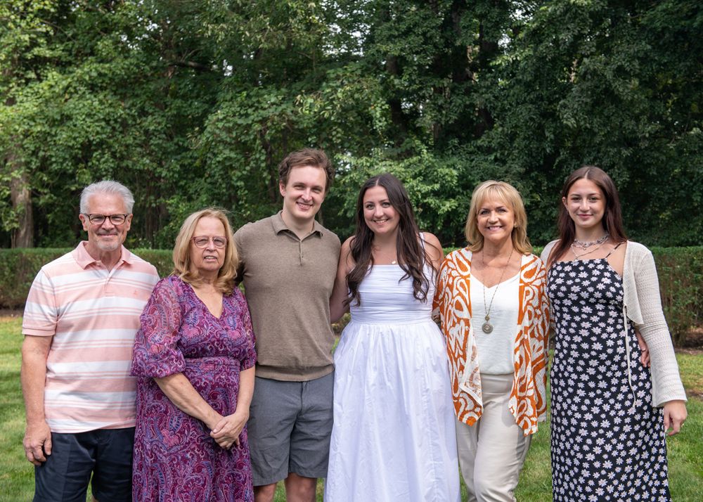 Group photo of six people at outdoor summer gathering.