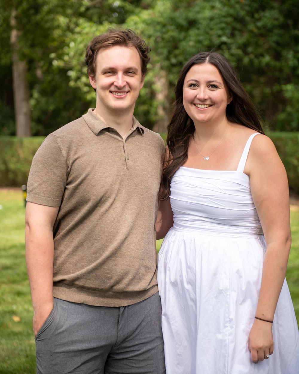 Couple in coordinating casual outfits poses together on green lawn.