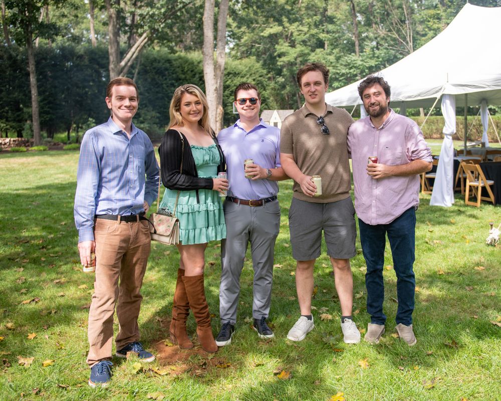 Five friends gather at outdoor party under tent canopy.