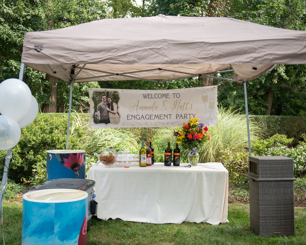Engagement party setup with white tent, balloons, and floral decorations in garden setting.