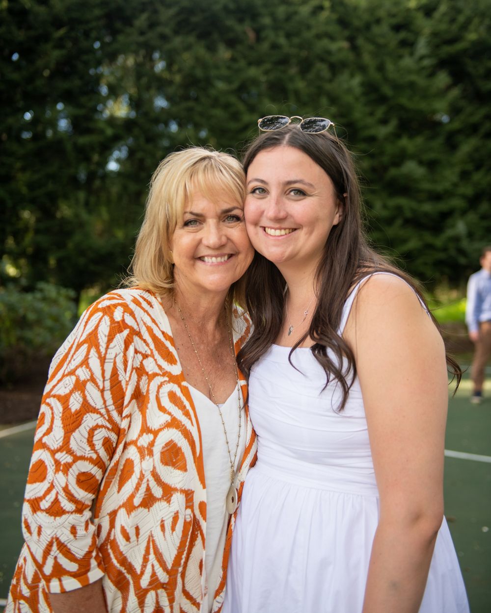 Two people embrace while smiling outdoors at summer celebration.