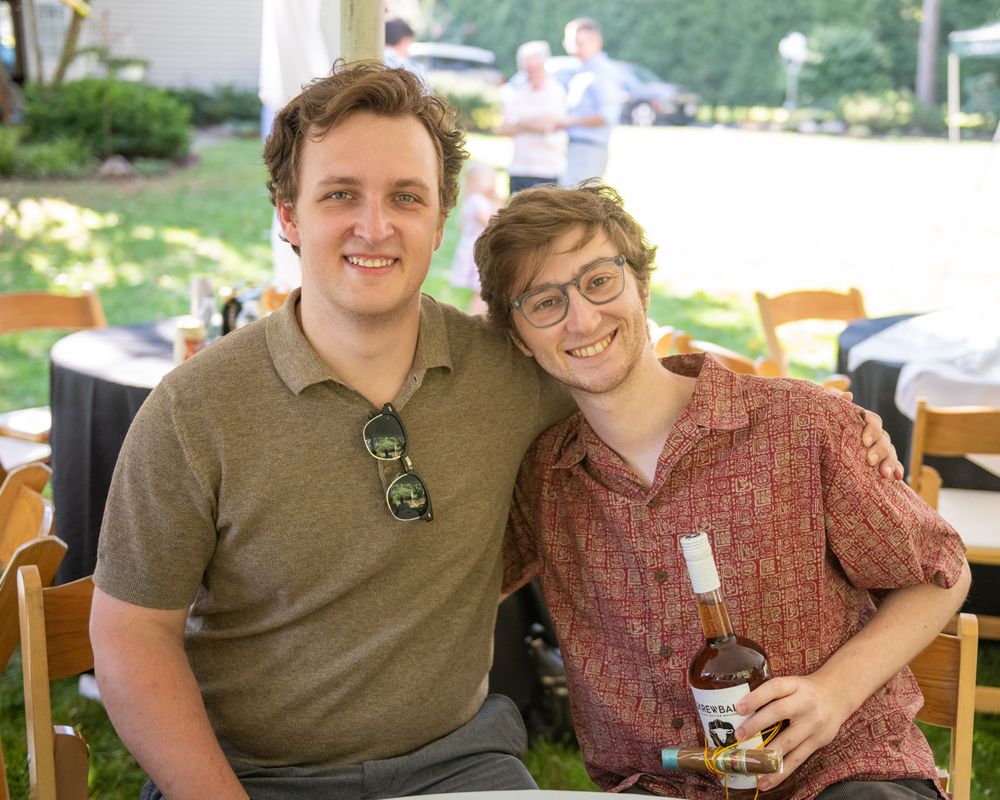 Two friends smiling for a photo at an outdoor gathering.