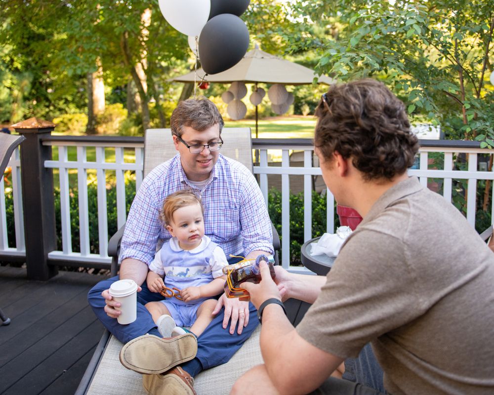 Adults chatting on a deck decorated with black and white balloons.
