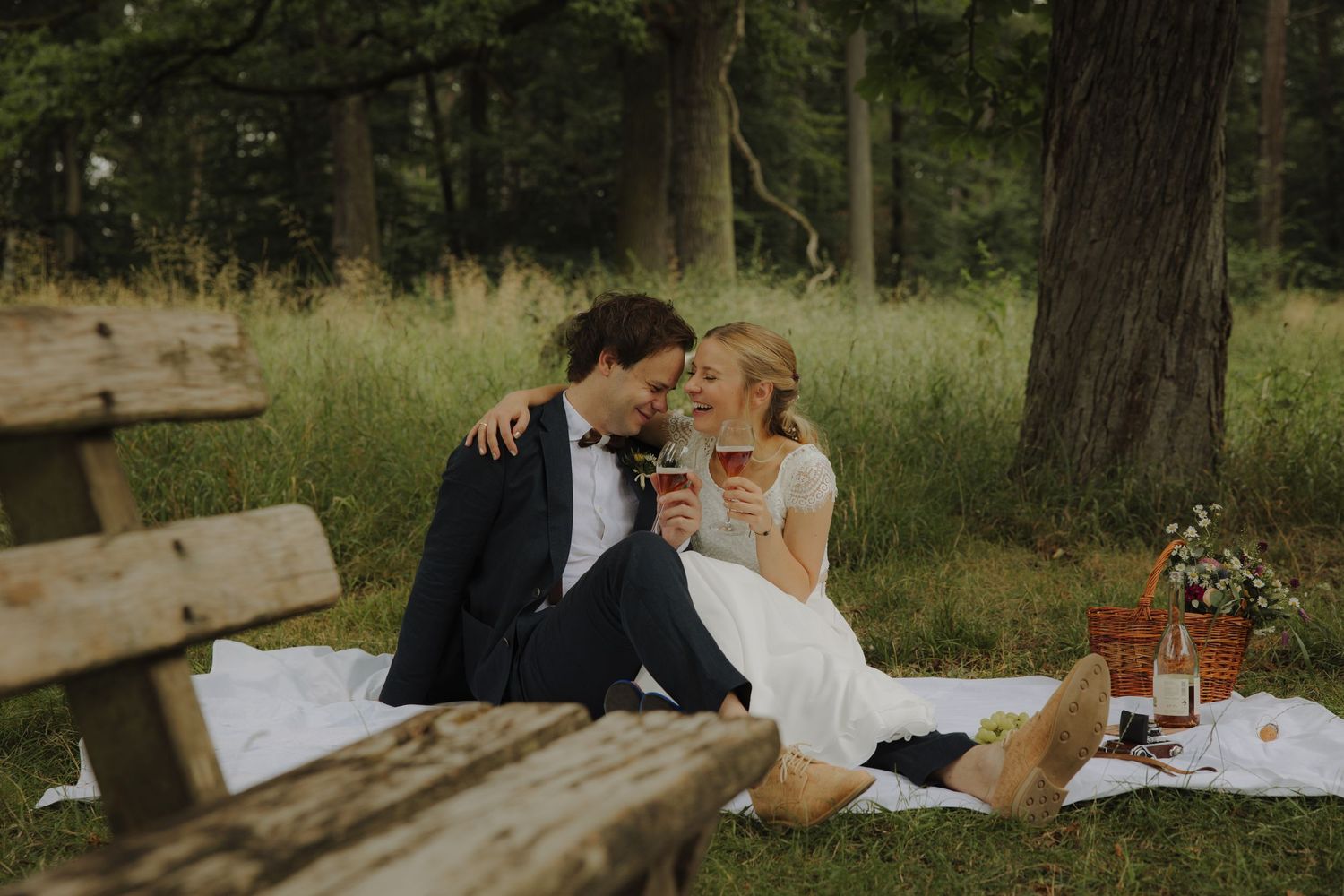 An intimate outdoor celebration picnic with wooden benches and natural woodland scenery.