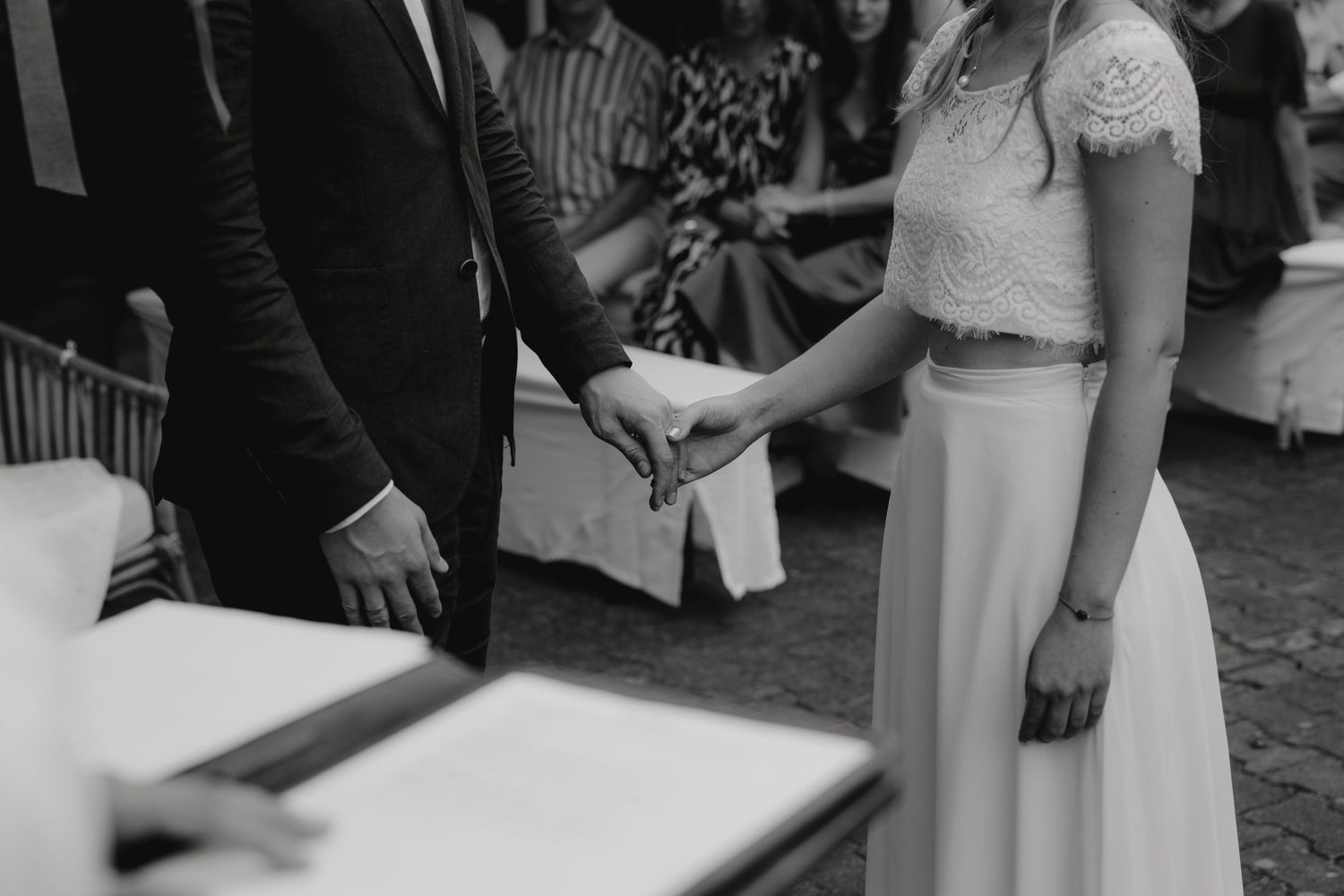 A black and white capture of a couple holding hands during their wedding ceremony.