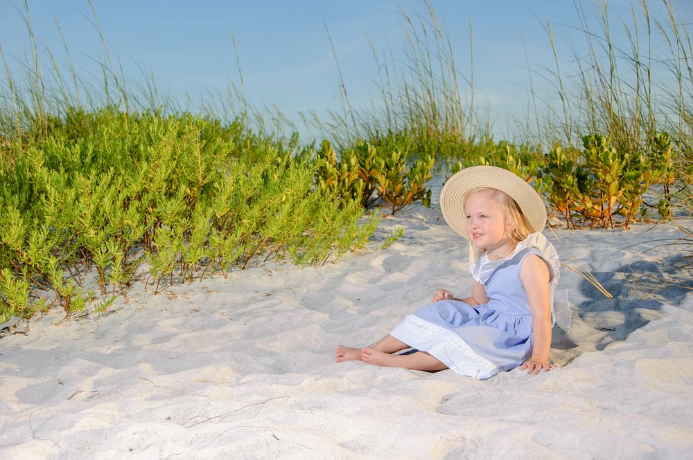photo of young girl in hat sitting on the beach in New Port Richey