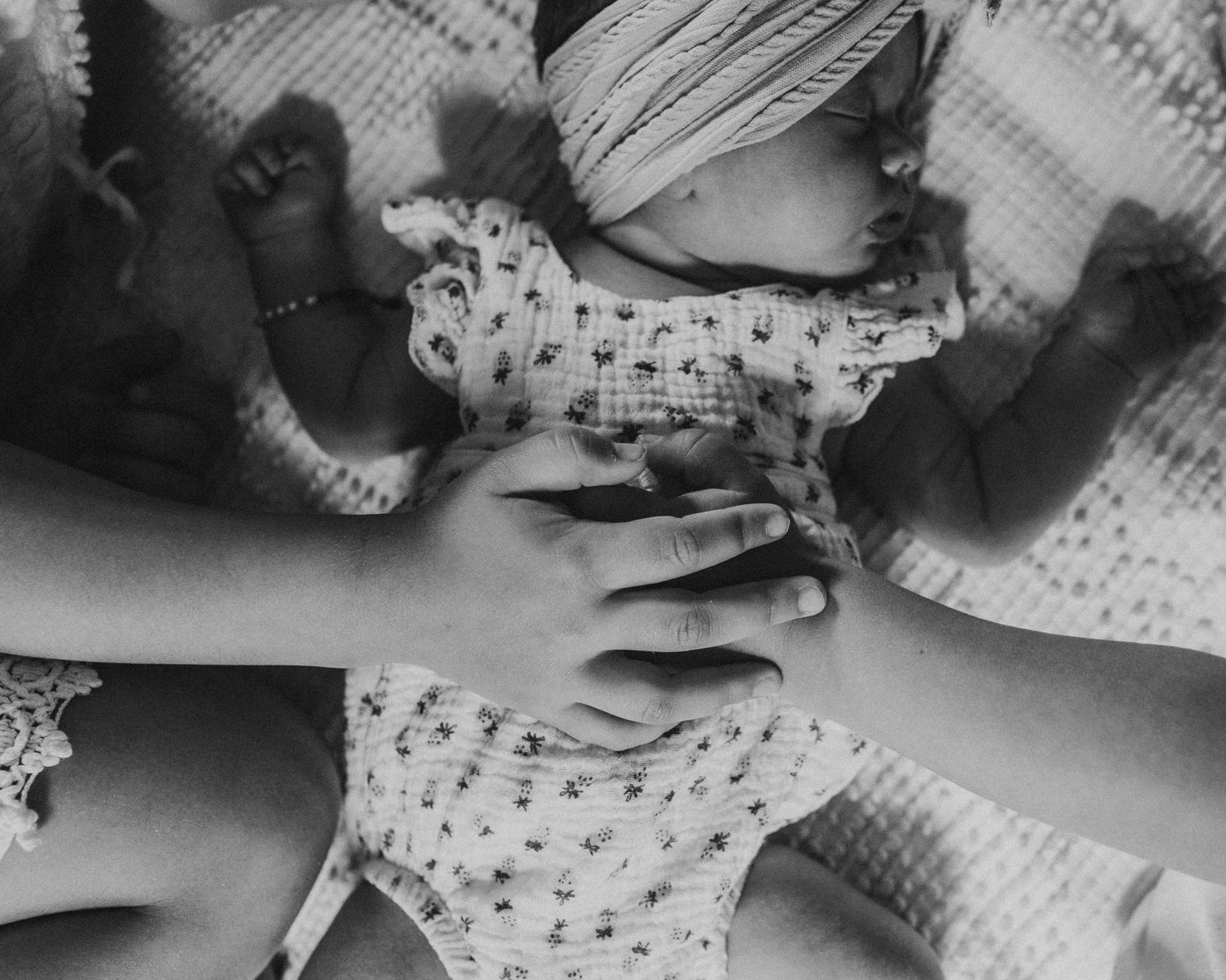 Two hands holding on to a newborn