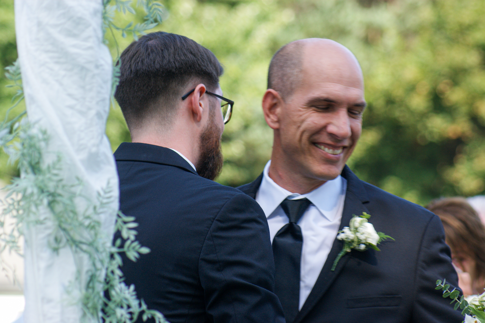 Outdoor wedding ceremony moments with guests in natural garden setting.